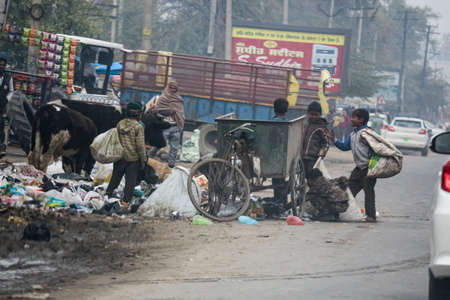 Child labour rag picker picking up plastic waste from the streetのeditorial素材