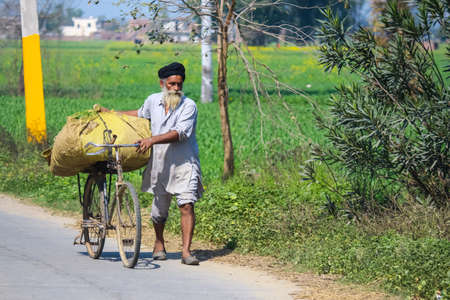 A farmer riding on a bicycle while working in his fieldsのeditorial素材
