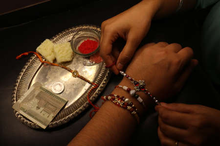 Happy Raksha Bandhan a sister tying rakhi thread on brother's hand with rakhi decorative thaliの写真素材