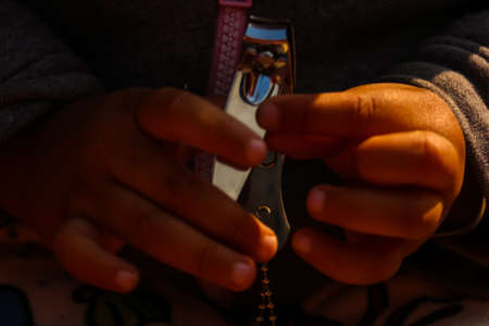 Close up of a kids hand cutting nails with nailcutterの写真素材