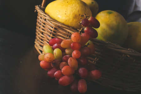 still life with fruits grapes mango on black backgroundの写真素材