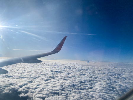 wing view from airplane window blue sky with a spread of clouds and shade of sunlightの写真素材