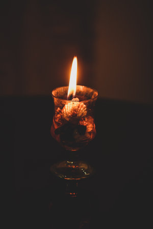 burning candle flame in the glass with shells celebration occasion celebration in darkの写真素材