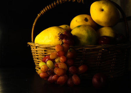 basket of fruits mango grapes on black background freshness healthyの写真素材