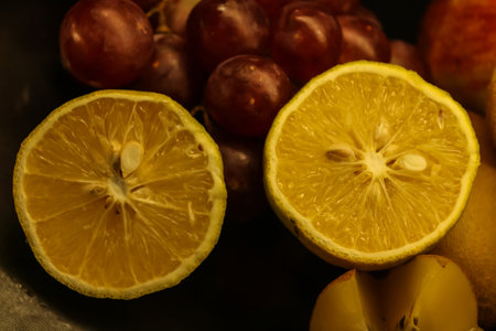Closeup of half cut citrus orange mausambi with grapes fresh fruit backgroundの写真素材