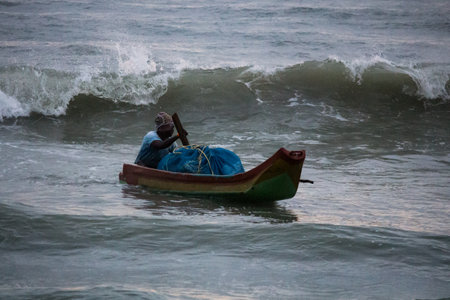 fisherman rowing in tides while fishing in the seaの写真素材
