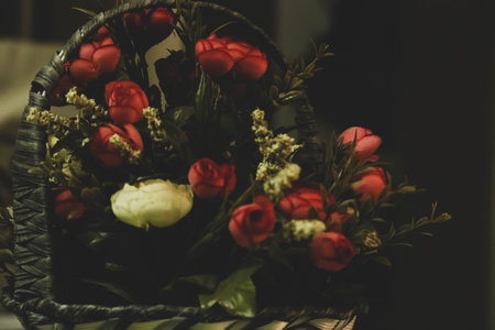 Basket of red roses in vintage style, selective focus, vintage tone with few white flowers and black...