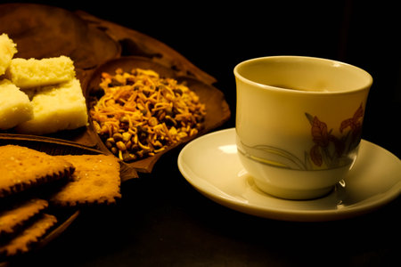 Cup of tea and biscuits on a wooden plate on a black background. Close-up food photography.の写真素材