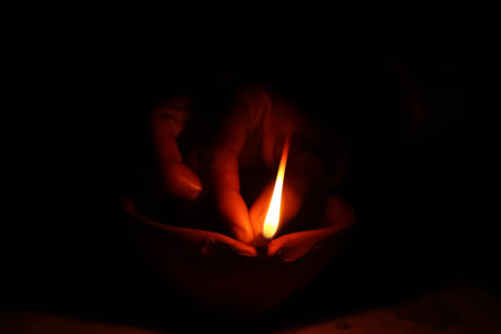 Hands of a woman lighting a Diwali oil lamp diya in a clay pot. Happy diwaliの写真素材
