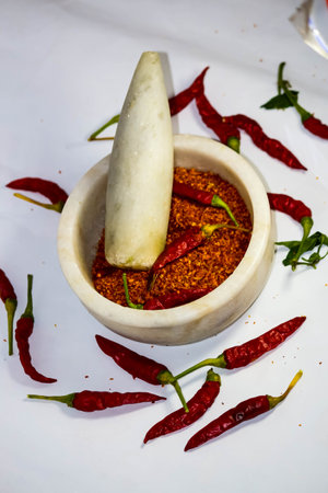Red chilli powder in a mortar with chilli pepper on white background. Food background backdrop wallpaperの写真素材