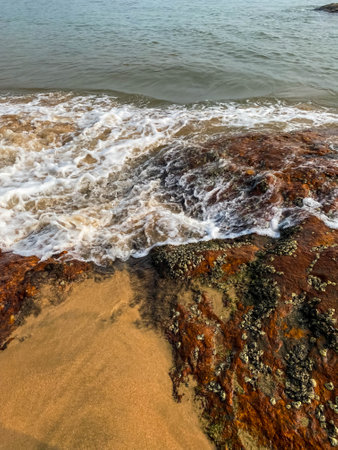 Closeup of Rocky coast. Water waves touching red rocky fungi stones of Gokarna Karnataka Indiaの写真素材