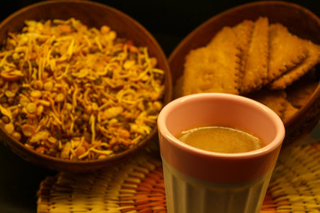 Cup of Indian Masala tea with snacks with Selective focus on black background. Close up. Tea-time refreshment.の写真素材