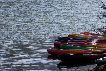 Row of colorful kayaks on the riverbank with water reflections. Beautiful Nature background landscapeの写真素材