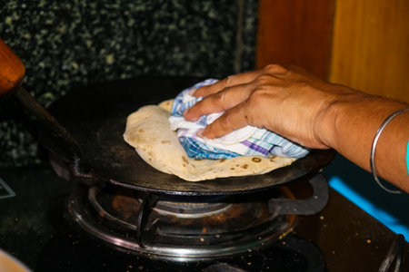 Cooking Indian Wheat Chapati pancakes on a gas stove in the kitchen at home. Homemade healthy food.の写真素材