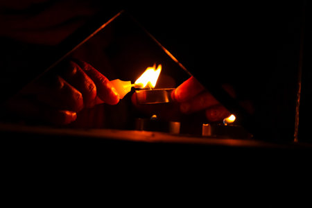 Man lighting a candle in a dark room. Selective focus.