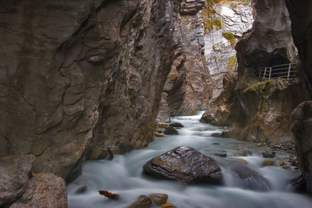 The rough mountain river Aareshljuht in Switzerland and a path for tourists with a handrailの写真素材