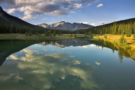 Mirror reflection of the sky and clouds in water of mountain northern lake