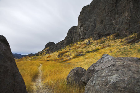 A footpath between stones in a yellow grass near to stone breakageの写真素材
