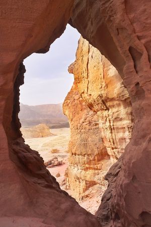 Through huge arch in ancient red mountains in desert of Israelの写真素材