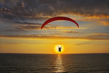 Operated parachute above the sea on a sunsetの写真素材