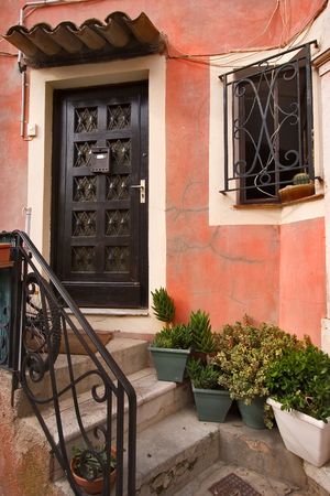  An ancient wooden carved door, a window with a figured lattice, stone steps and flowers in potsの写真素材