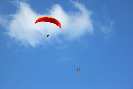 The operated red parachute flies in high in the blue skyの写真素材