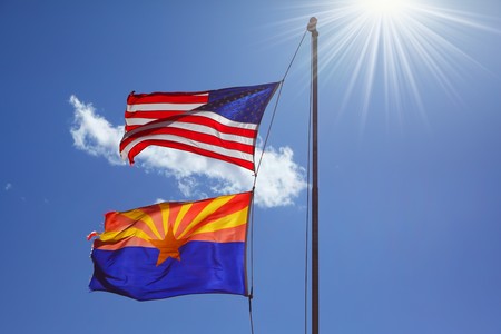 Flags of the United States and the Navajo Reservation are flying against the shining sunの写真素材