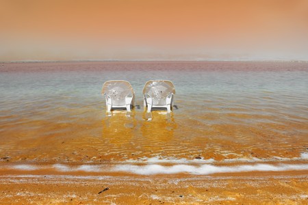 White beach armchairs in the warm clear water beach. Beach on the Dead Sea, a sunny day in Mayの写真素材