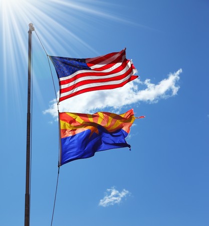 Flags of the United States and the Navajo Reservation are flying against the shining sunの写真素材