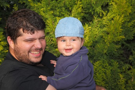 Happy young father playing with his little son in the coniferous forestの写真素材