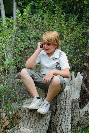 Beautiful blond  boy  talking on a mobile phoneの写真素材