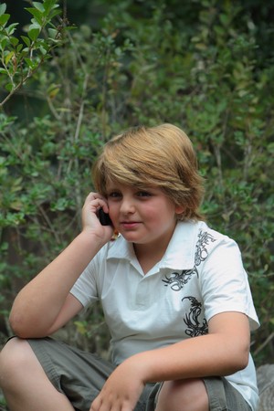 Beautiful ten years' boy with light golden hair talking on a mobile phoneの写真素材