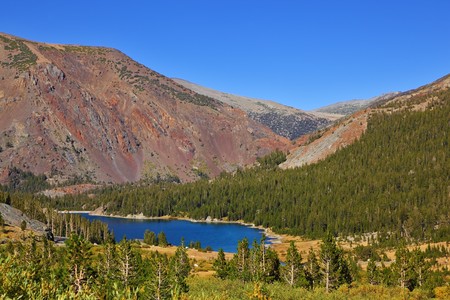Picturesque huge red mountain on coast of dark blue lake Tioga in park Yosemite, the USAの写真素材