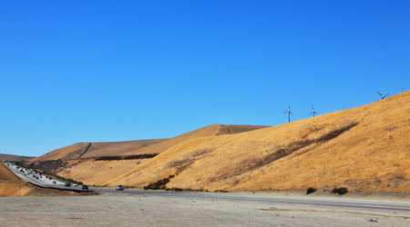 Soft hills of California. An autumn yellow grass and windmills on horizon
