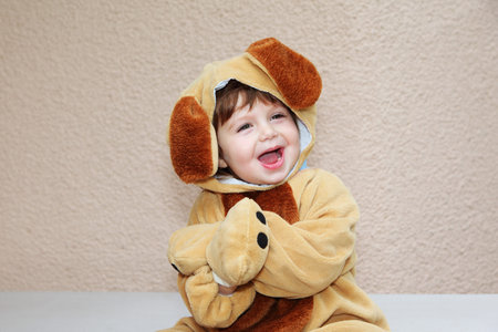 The charming little boy in a fluffy suit for a carnival with long ears cheerfully laughsの写真素材