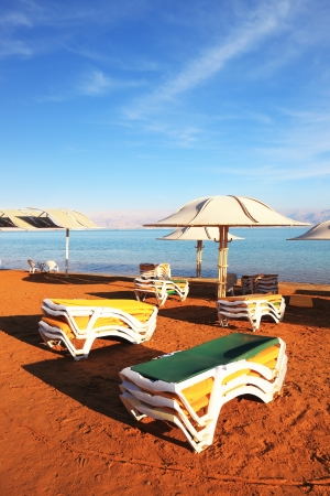 Beautiful sunny day at a beach resort. The Dead Sea, the green beach chairs and umbrellas waiting for touristsの写真素材