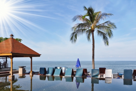 The luxurious marble pool on the island of Koh Samui. Palm tree and beach chairs are reflected in the smooth surface of the waterの写真素材
