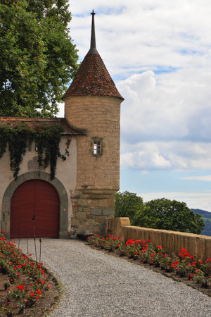 The medieval castle in Upper Savoy  Corner round tower, part of the protective walls and massive red wooden gateのeditorial素材