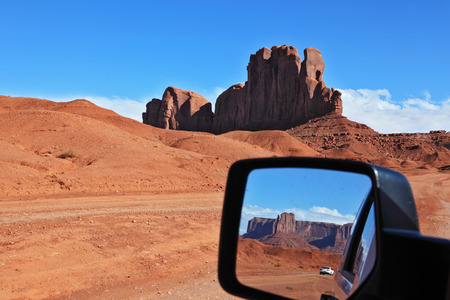 The famous cliff "Camel" and other cliff of red sandstone in Monument Valley are reflected in the car mirror. Navajo Reservation in the U.S.の写真素材