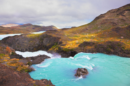 Gorgeous National Park in Chilean Patagonia. Affluent bustling Salto Grande waterfall with emerald water. On the edge of the cliff stands woman- touristのeditorial素材