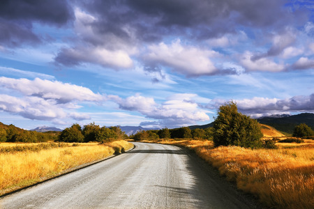 The beginning of autumn in the southern Patagonia. Amazingly beautiful sunset illuminates the distant mountains and the dirt road with bright lightの写真素材
