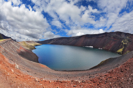 Iceland in July. Oval blue lake in the crater of the volcano cooled down. Steep banks of the lake of red rhyoliteの写真素材