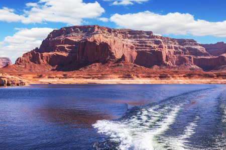 Foamy trace of motorboat crosses the emerald waters. Red sandstone hills surround the lake. Lake Powell on the Colorado Riverの写真素材