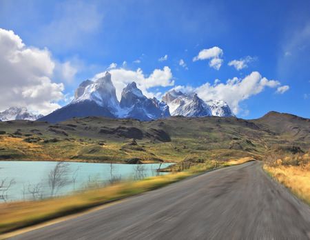A trip at high speed. Dangerous driving in the national park Torres del Paine, Chile. A gravel road runs by the lakesideの写真素材