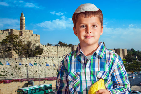 Charming seven year old boy in white festive skullcap with etrog. Sukkot in Jerusalemのeditorial素材