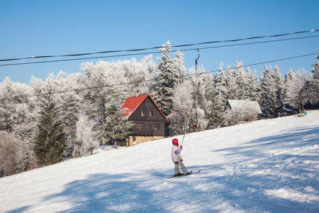 SKI CENTER KOHUTKA, CZECH REPUBLIC - JANUARY 16, 2010: Ski resort in the Czech Tatra. Frosty sunny winter day. Skier in a red helmet standing on the liftのeditorial素材