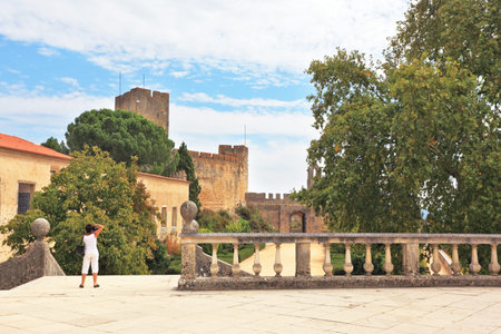 The imposing medieval castle - the monastery of the Templars. A woman dressed in white photographs in the parkのeditorial素材