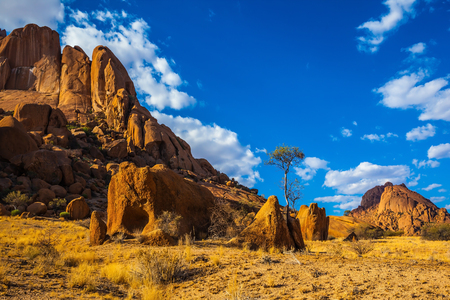 Nature reserve Spitzkoppe in Namibia. Picturesque stone arches are painted by iron oxides in red-orange color. Evening sun lengthens the shadows among the rocksの写真素材