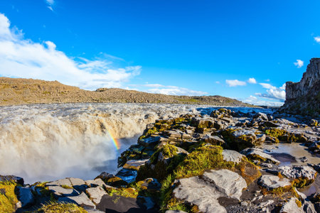 Colossal Dettifoss waterfall in Iceland. Sunset on a summer day,  magnificent rainbow in the water...