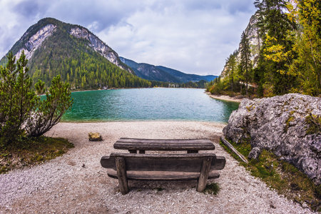 Wooden table and benches for picnics by the lake. Lago di Braies, South Tyrol, Italy. The concept of walking and eco-tourismの写真素材